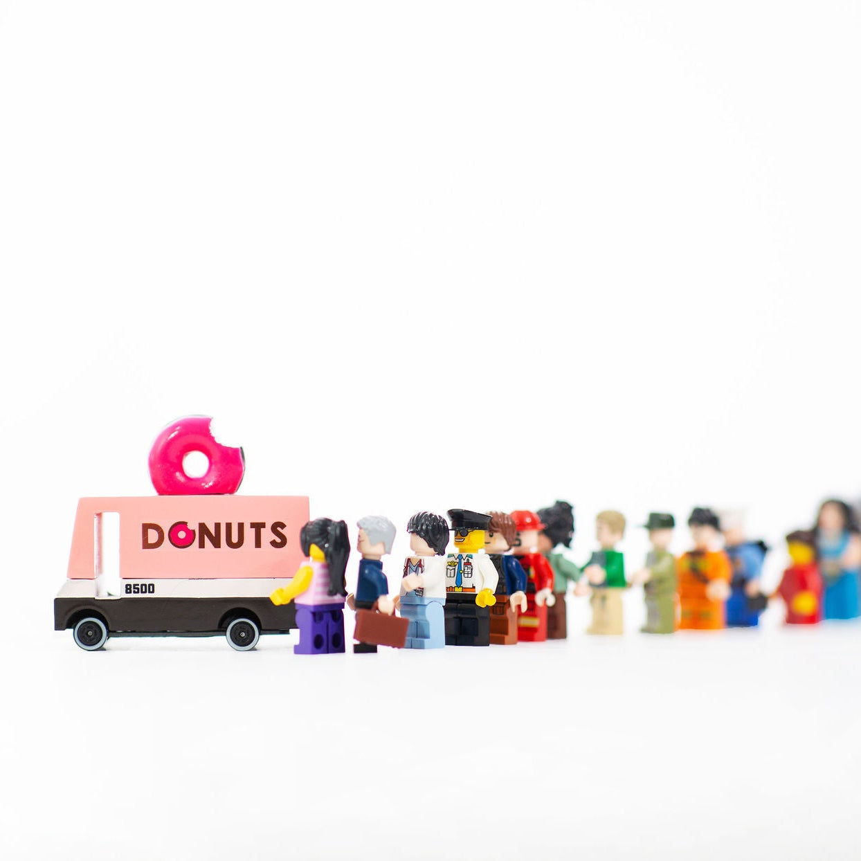 Toy donut truck with a line of small figures on a white background