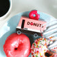 Donut truck toy on a plate with pink donut and coffee cup