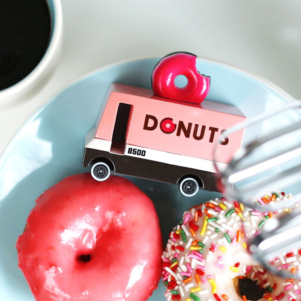 Donut truck toy on a plate with pink donut and coffee cup