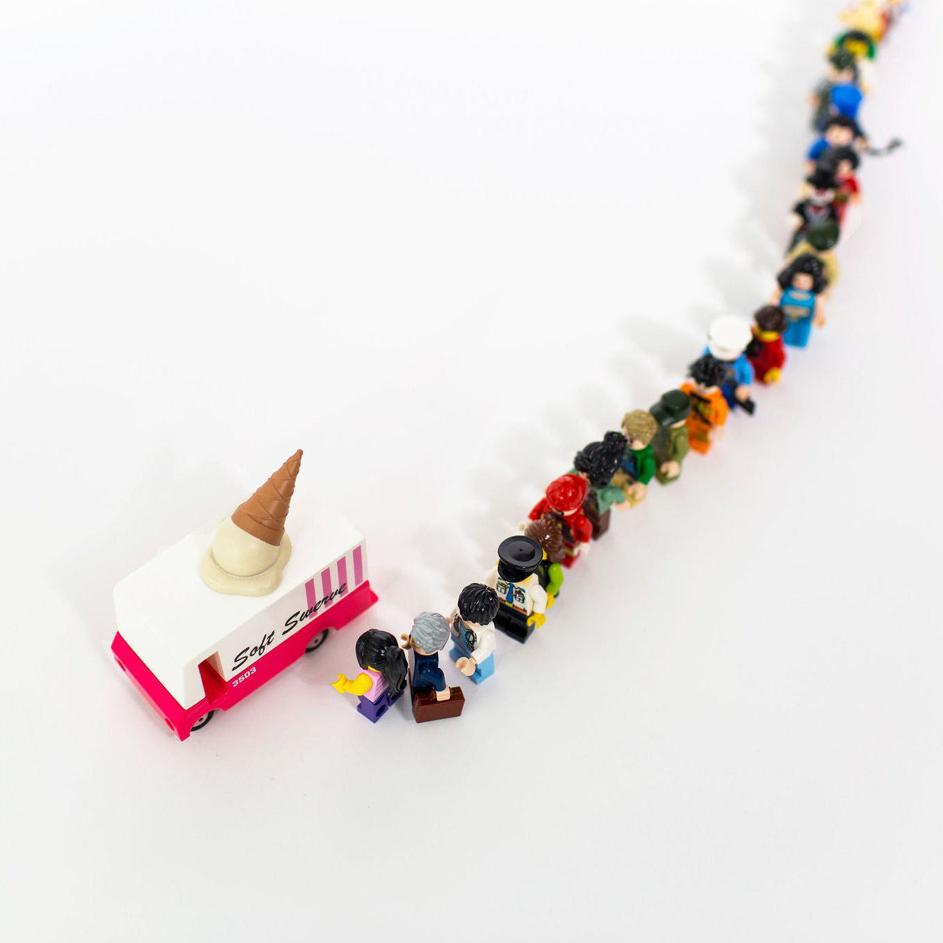 Colorful toy figures in a line with a ice cream truck and cone on a white background