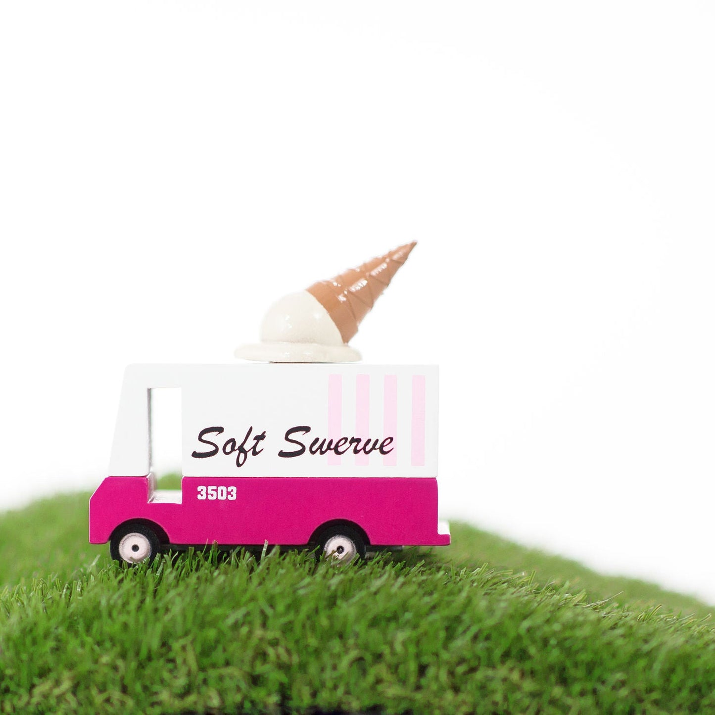 Model of a pink ice cream truck with an ice cream cone on top, labeled 'Soft Swerve', on a grassy surface.