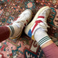 White sneakers with red and blue accents worn on a patterned rug