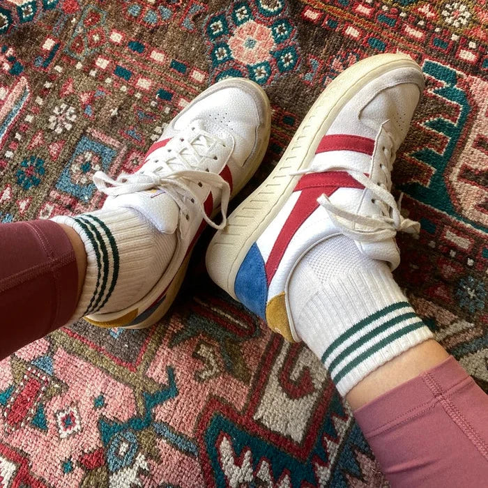 White sneakers with red and blue accents worn on a patterned rug