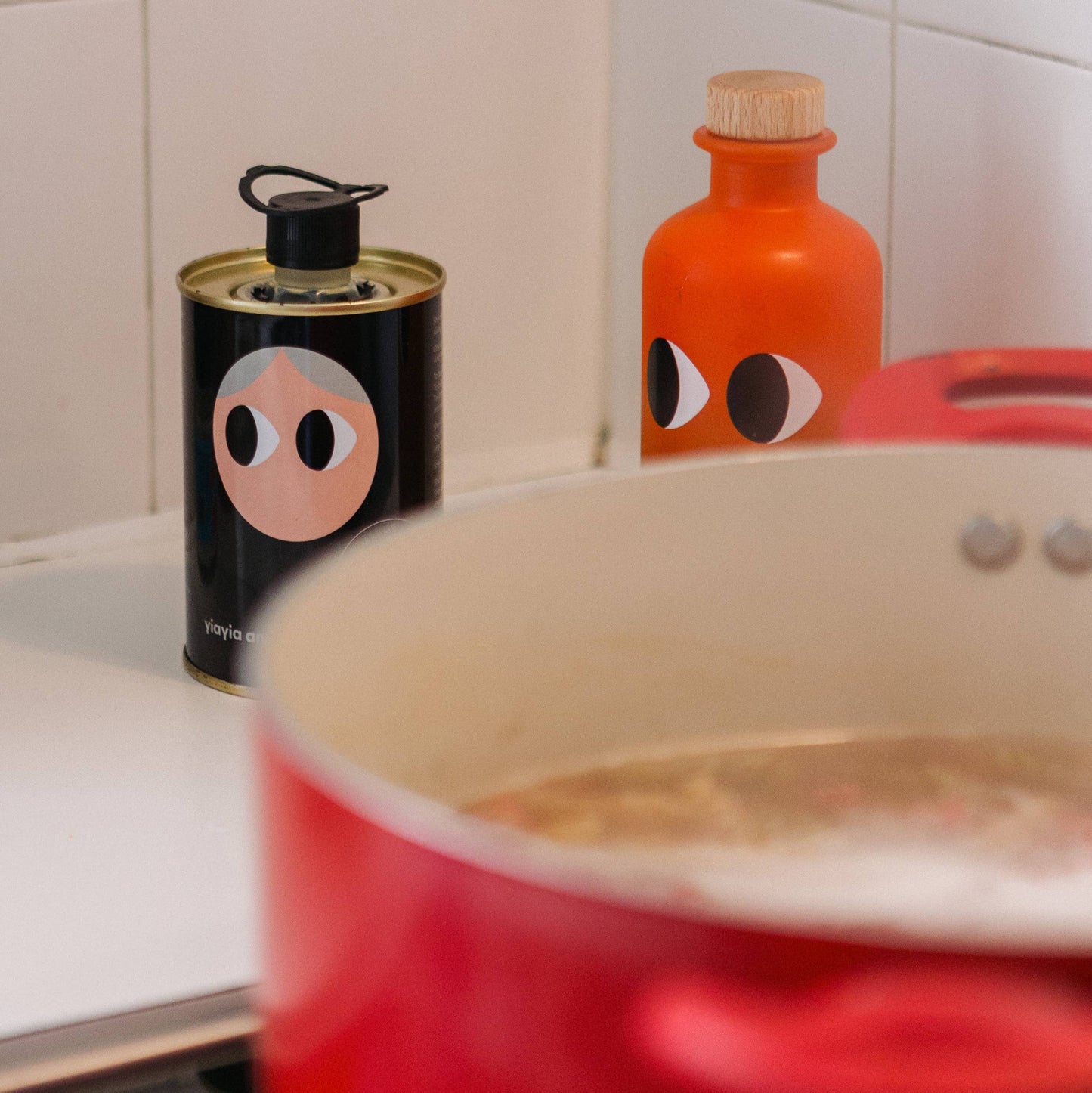 Two bottles with face designs on a kitchen counter next to a pot.