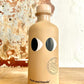 Beige bottle with eye design on a wooden surface