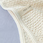 a close up detail image of the fog linen label on the waffle knitted cream blanket, which is sewn into the boarder of the blanket