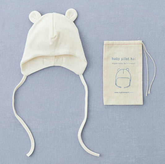 Fog Linen baby pilot hat in natural ivory, made from 100% organic cotton. The hat features a lined interior for comfort, designed for newborns up to 3 months old, and is packaged in a reusable stamped muslin pouch