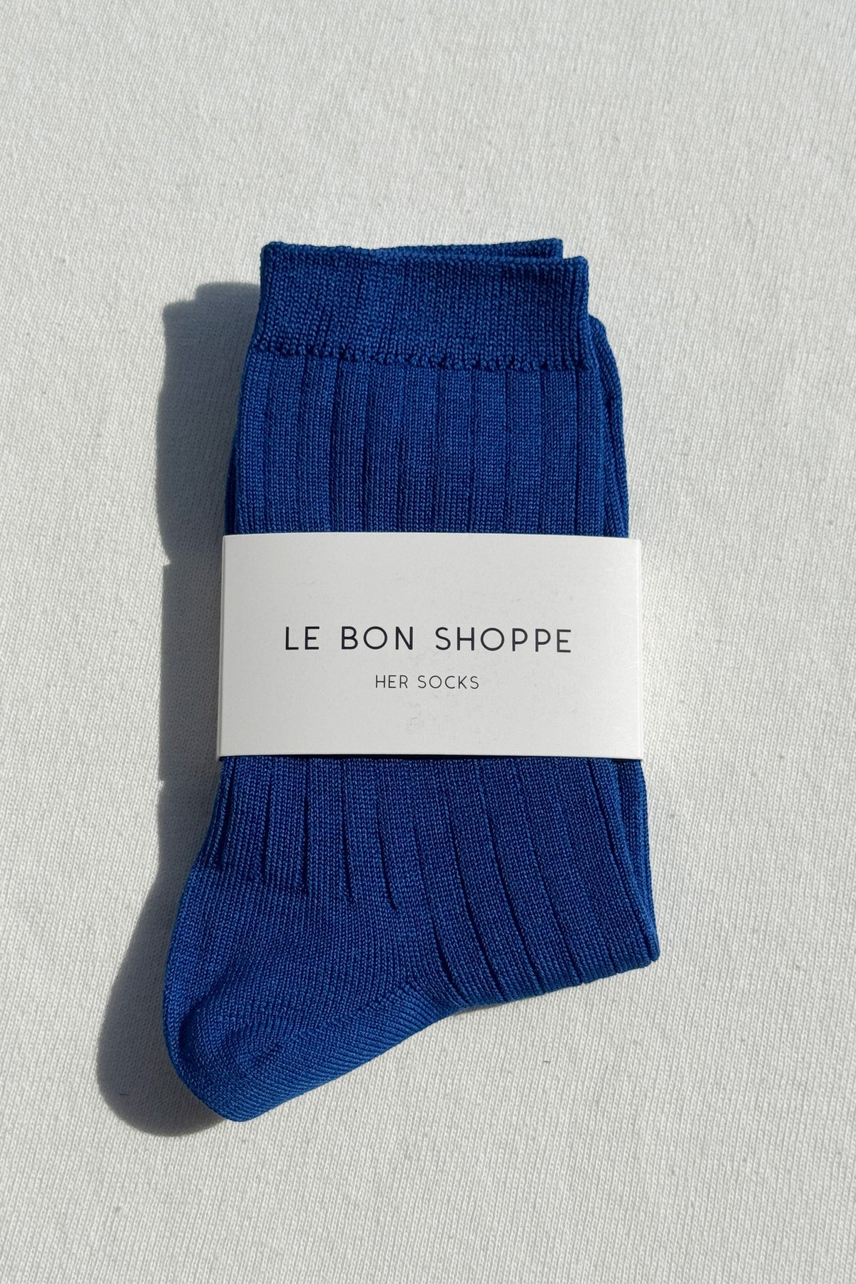 Pair of blue socks with a white label on a light gray background