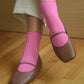 Brown shoes with pink socks on a wooden floor