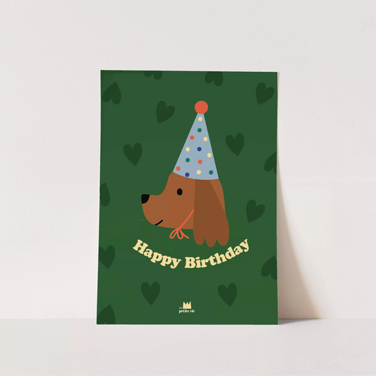 A playful birthday postcard or mini print featuring a deep green background with a subtle heart pattern. The design showcases an illustrated brown dog wearing a polka-dotted party hat, with "Happy Birthday" in bold, yellow vintage-style text.