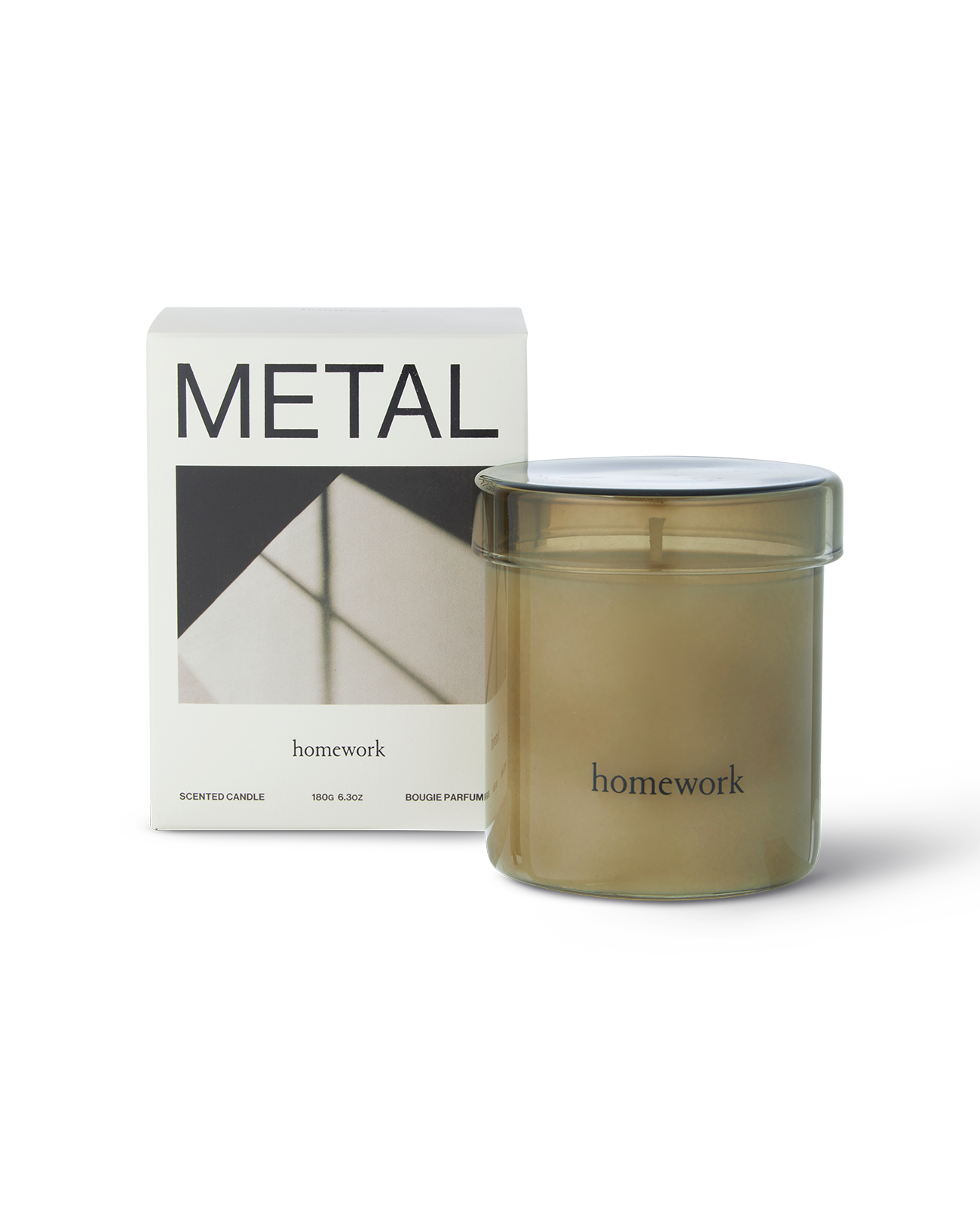 Homework metal scented candle in a moss green glass with matching lid, along the bottom the branding spelling homework in lower case lettering. Next to its packaging, a white box with metal written across the top and a landscape image of shadows on metal below.