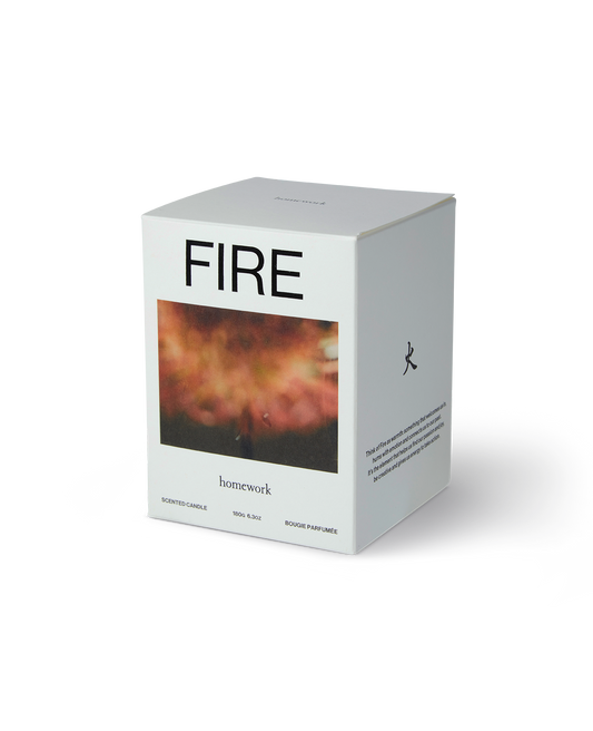 The homework candle packaging in fire, a white box with fire spelt across the top and under this a landscape image of a blurred fire in red tones. Then the brands name homework written under the images in lowercase