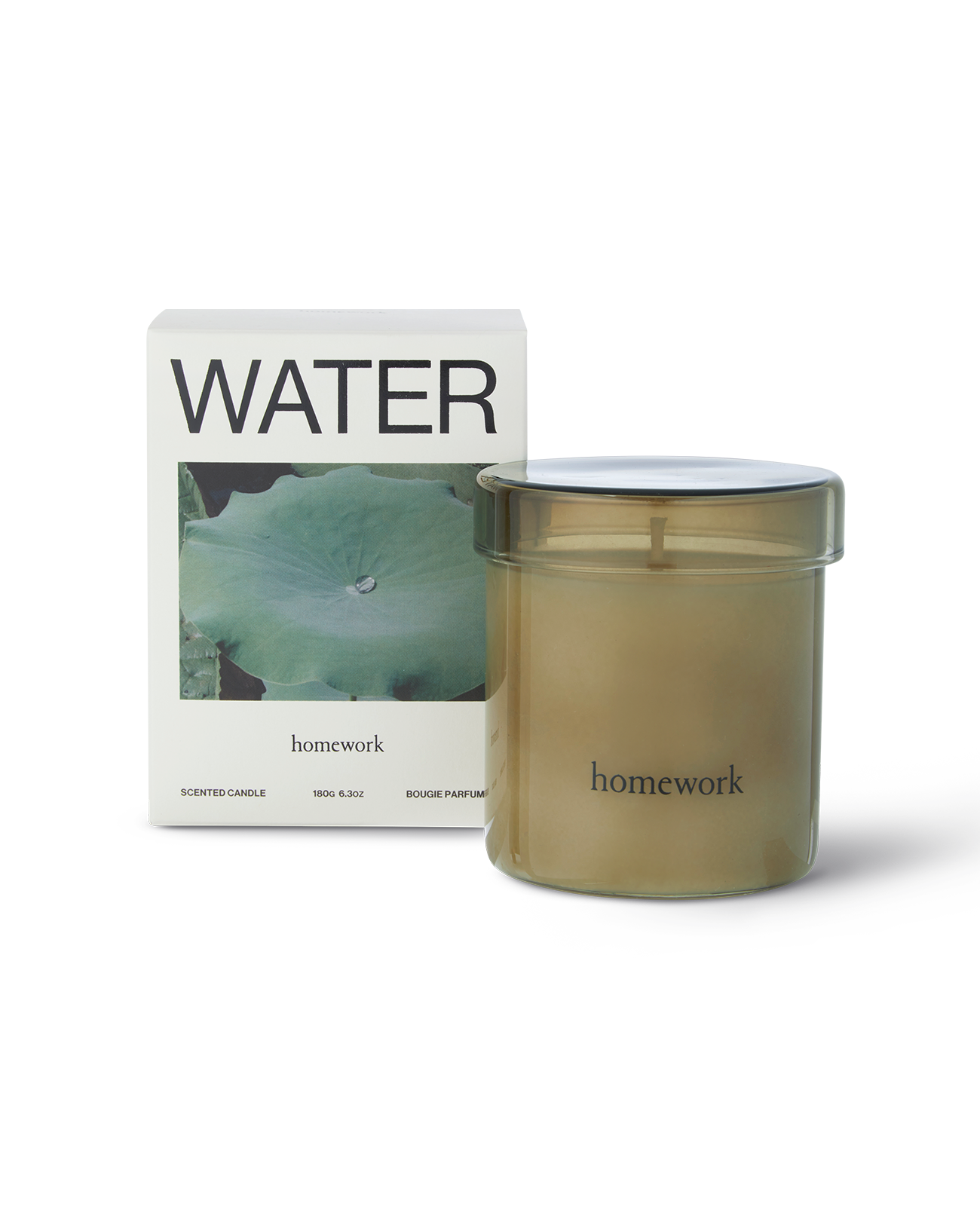 Homework water candle in a moss green cylindrical transparent glass with matching lid, along the bottom small branding spelling in lower-case lettering is homework. Next to the candle is the packaging a box with water written along the top, under is a landscape image of a green waterlily pad with a single water droplet on it. And under is the brands name homework in smaller lowercase lettering