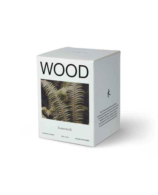 Homework wood candle packaging, a white box with wood spelt across the top, under an image of a brownish green Fern plant an the brands name in lower case lettering under the photo