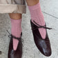 Person wearing pink socks and black shoes on a concrete surface