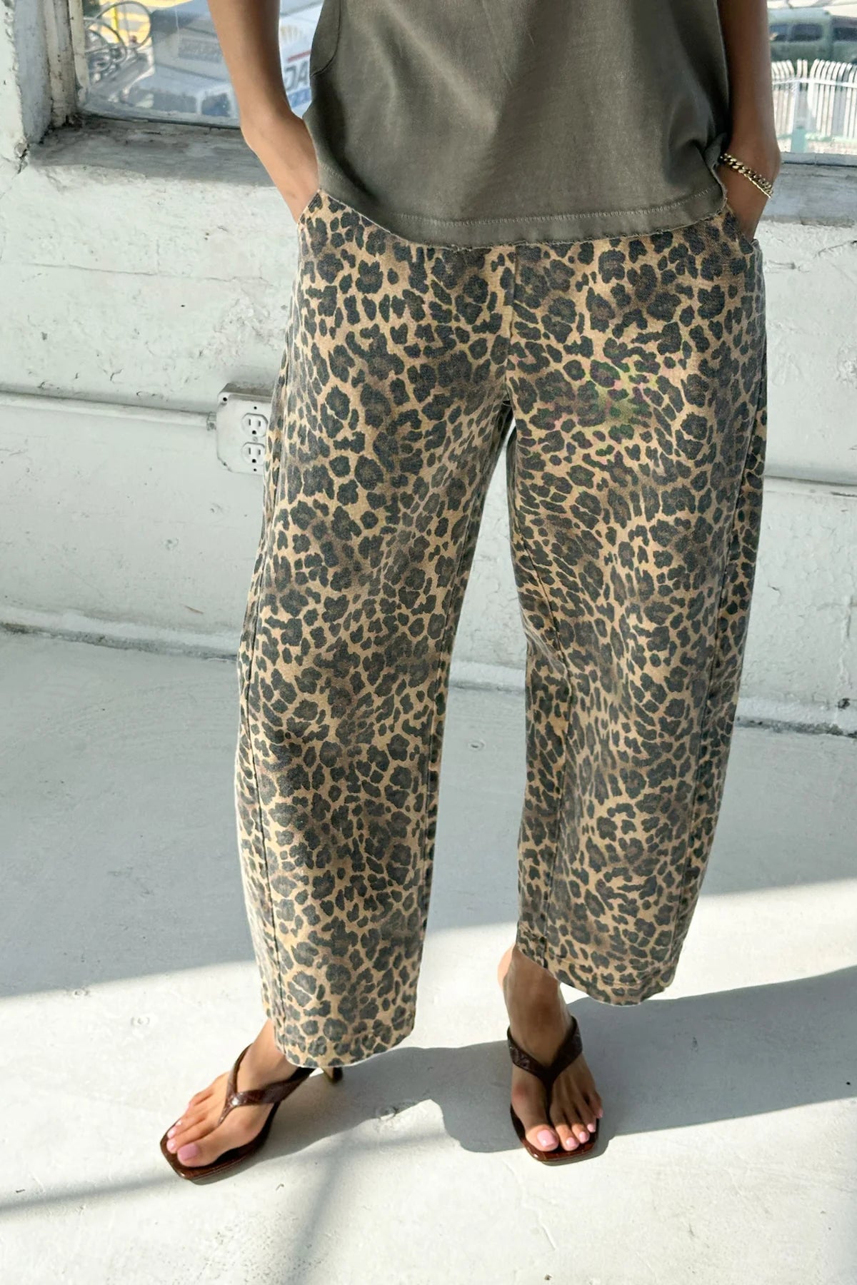 Person wearing leopard print pants and a green top on a light-colored floor.