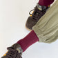 Person wearing maroon socks, green pants, and brown sneakers on a white background