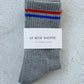 Gray socks with red and blue stripes on a textured white surface, featuring 'Le Bon Shoppe' label.