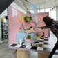 Studio setup with pink tiled wall, checkered floor, and various props.