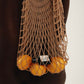Person wearing a brown net bag filled with lemons on a plain background