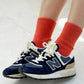 Navy blue sneakers with white laces and red socks on a light gray background