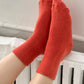 Red socks being worn on a white surface