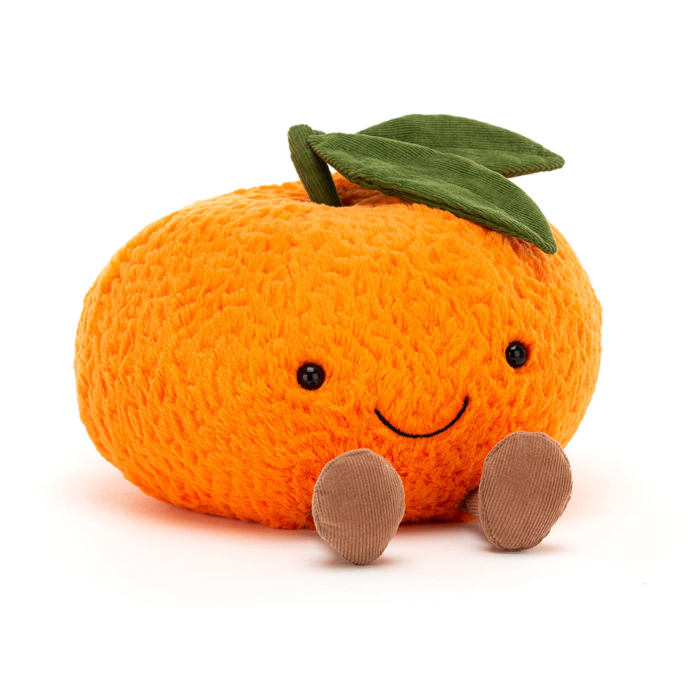 A plush toy in the shape of an orange. The orange, which is also the colour orange is textured and has a green stem with two green leaves coming out the top of it. The orange has a black small and two eyes, which appear to be  beads. At the bottom of the orange there are two brown feet, making the orange 'sit down'. This is against a white background. 