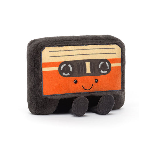 A playful Jellycat Amuseables Cassette Tape plush toy with a soft grey body, cheerful embroidered face, and colourful label details, featuring brown corduroy legs and a quirky, nostalgic design.