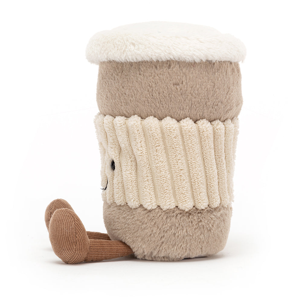 A soft, plush coffee cup with a friendly face and textured lid, featuring a little handle. The coffee cup is part of the Jellycat Amusables collection, designed to resemble a to-go coffee cup, and has a cozy, cuddly appearance. Shown from the left hand side