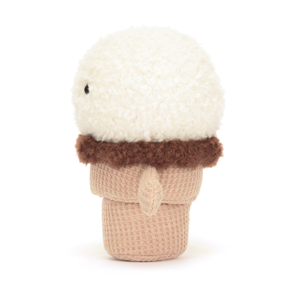 A soft, plush ice cream cone featuring a smiling scoop of ice cream on top and a textured cone base. The ice cream scoop is colorful and whimsical, part of the Jellycat Amusables collection, designed for cuddling and play. The overall design is charming and inviting, perfect for children and plush toy collectors.  Shown from the side