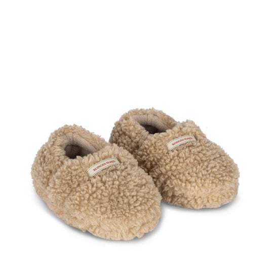 A pair of Konges Sløjd Globe Footies in a soft cream sherpa fabric, featuring a snug, slip-on design with a woven brand label on the front.