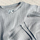 A close-up of the Konges Sløjd Minnie Body in gray dawn, highlighting the fine lace trim, bow detail, and delicate pointelle knit fabric.