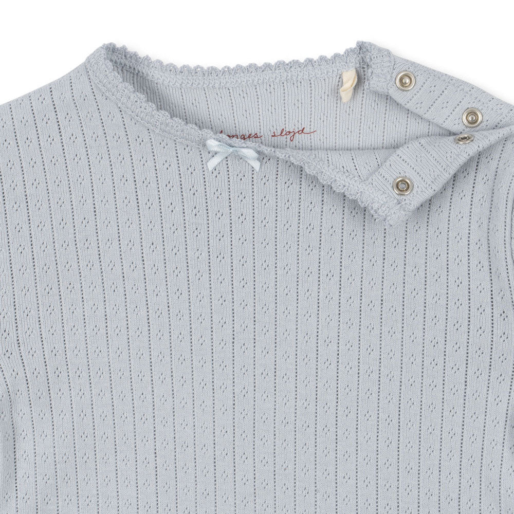 A detailed shot of the Konges Sløjd Minnie Body’s neckline, showing the snap button opening for easy dressing and soft lace trim.