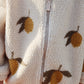 Detail shot of the Konges Sløjd Mon Grand Citron Jody Jacket's front zip – A close-up showcasing the fleece texture, silver zip, and yellow lemon pattern.
