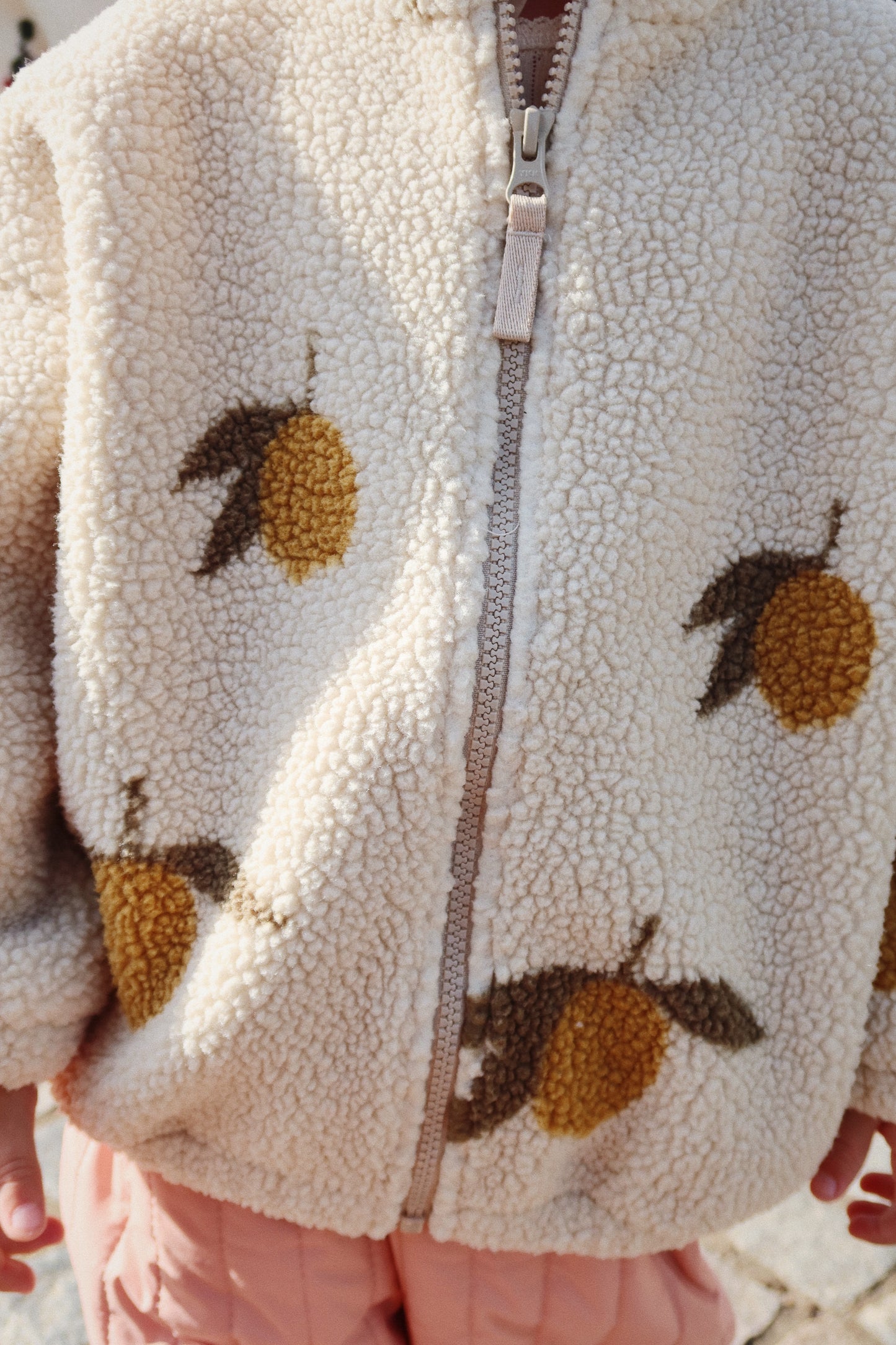 Detail shot of the Konges Sløjd Mon Grand Citron Jody Jacket's front zip – A close-up showcasing the fleece texture, silver zip, and yellow lemon pattern.