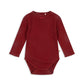 A deep red long-sleeve baby bodysuit by Konges Sløjd, featuring a delicate lace trim, tiny bow detail at the neckline, and soft ribbed fabric.