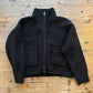 Black jacket with a zipper on a wooden surface