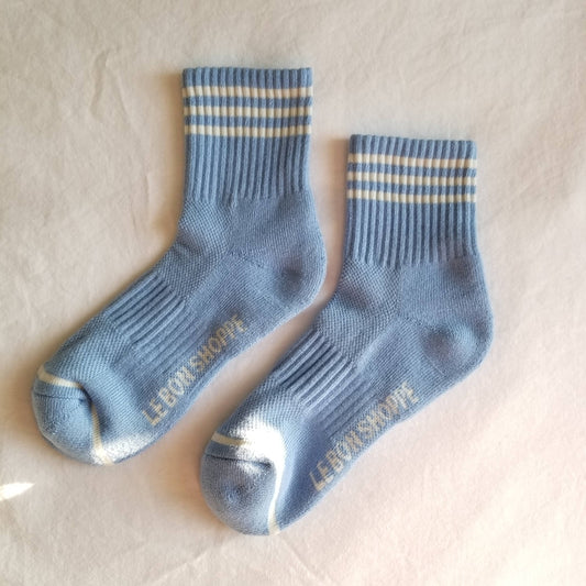 A pair of blue crew-length socks with a triple-contrast stripe at the top, branded with 'Le Bon Shoppe'.
