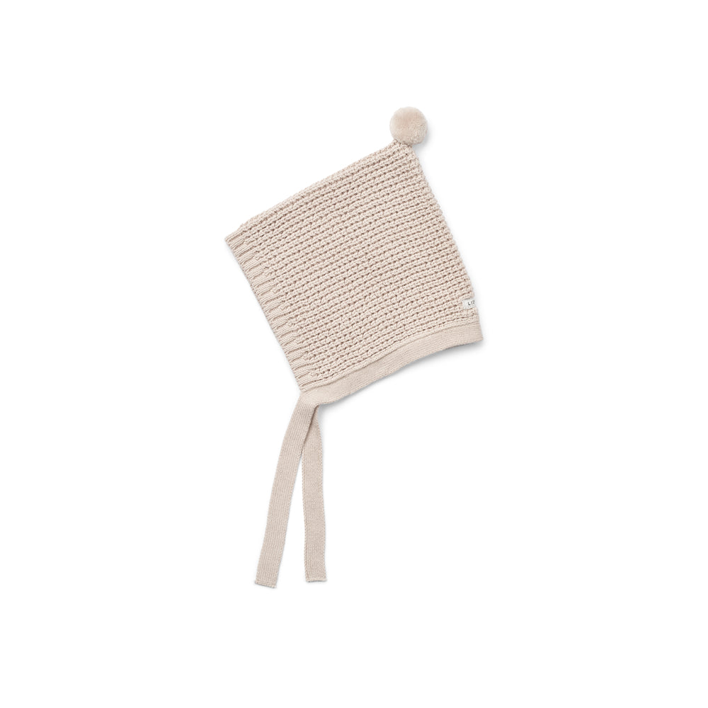 Liewood Fresia Baby Hat in Sandy, featuring a playful pompom on top, long adjustable strings, and delicate organic cotton knit