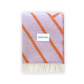 A folded Maison Deux blanket with lilac and orange lines and fringes on the short sides, displaying the brand name on a white label.
