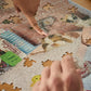 Person assembling a puzzle with a partially completed design of a cat and bird.