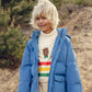 Child wearing a blue puffer jacket with a bear design in the background