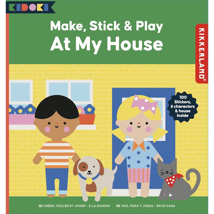 Make, Stick & Play – At My House craft kit packaging. The box features an illustrated yellow house with two smiling children, a dog, and a cat. A label highlights '100 stickers, 6 characters & house inside.' The Kidoki and Kikkerland logos are present, with multilingual text indicating the product’s name in French and Spanish.