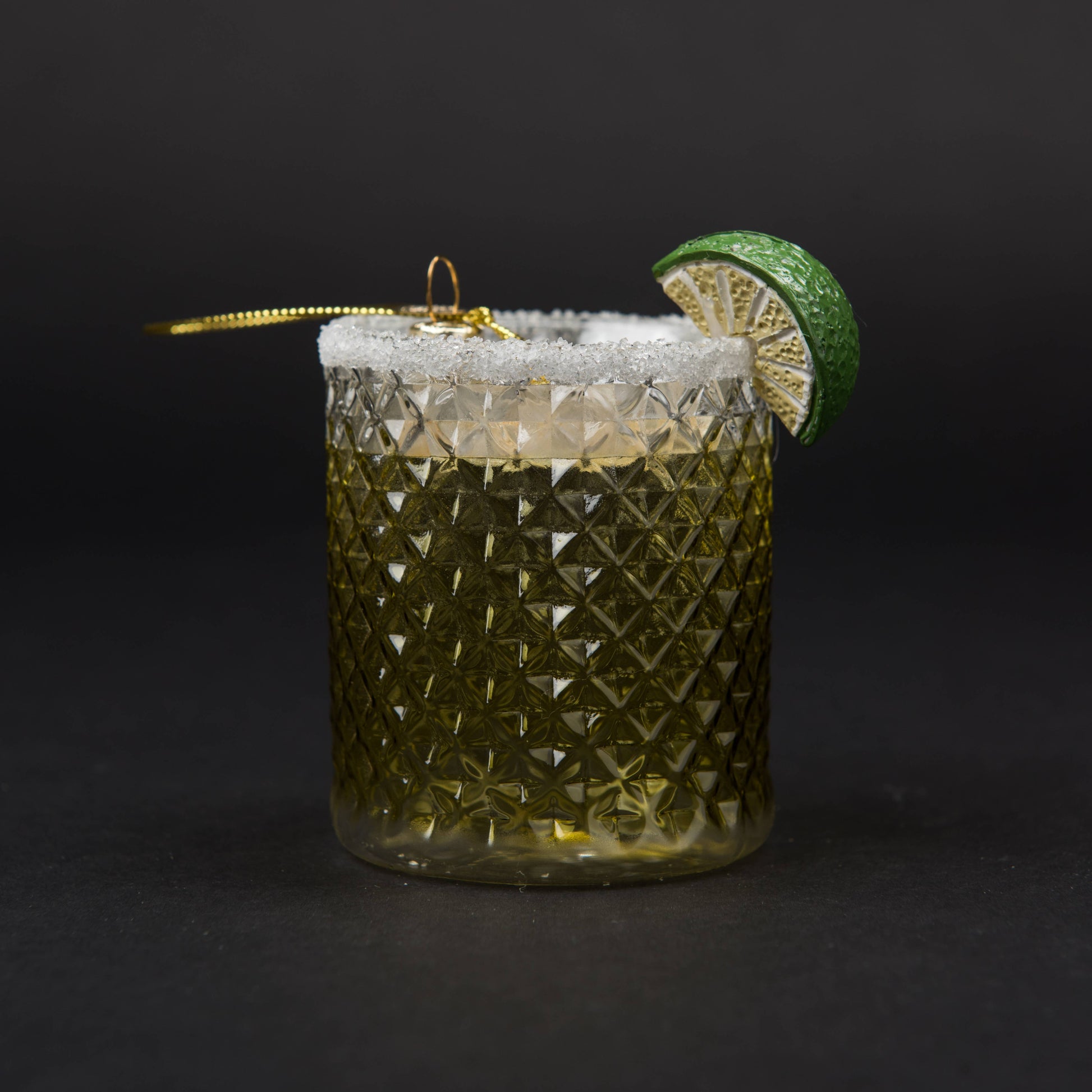 Hand-blown glass Margarita ornament featuring frosty ice, a salted rim, and a hand-painted lime wedge garnish stands against a stylish dark background