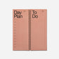 Pink spiral-bound planner with 'Day Plan' and 'To Do' sections on a white background