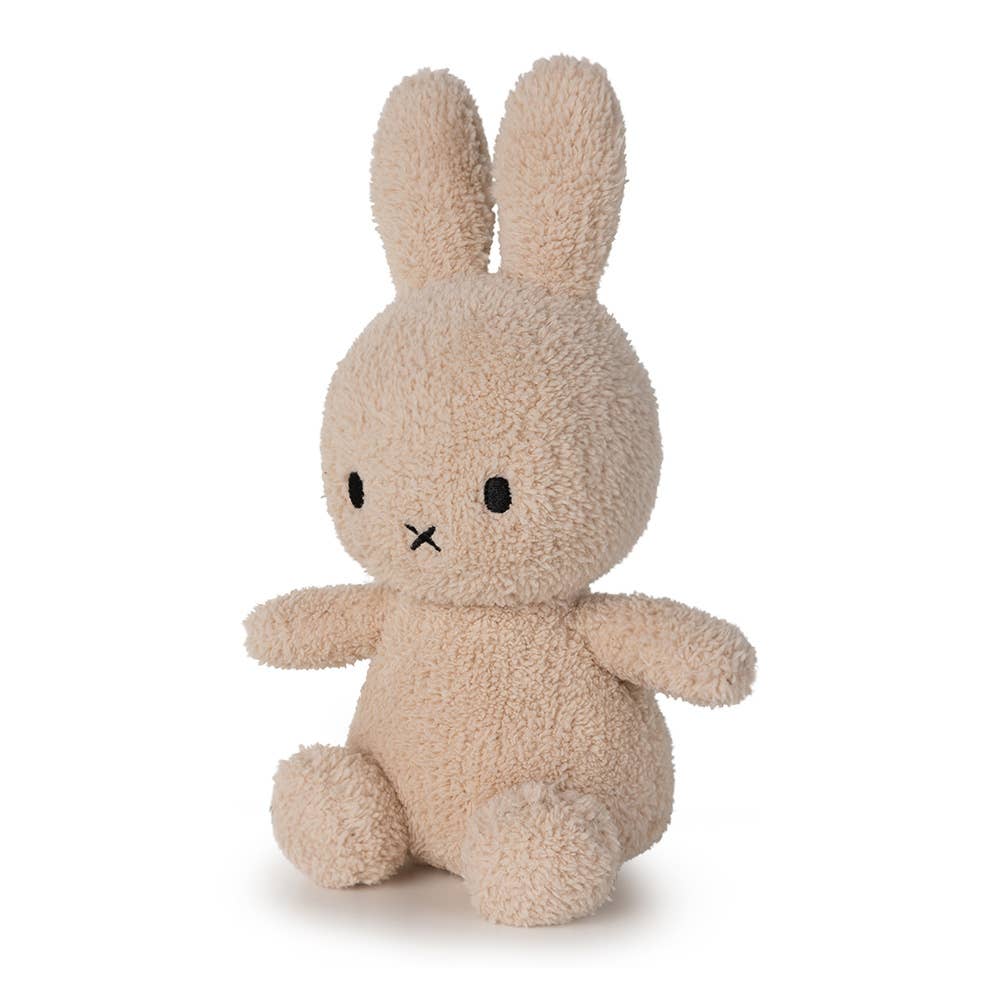 A MiffyTerry soft toy in the colour beige. This Miffy has black eyes and mouth. Miffy is 23 cm in height. The background is white. 