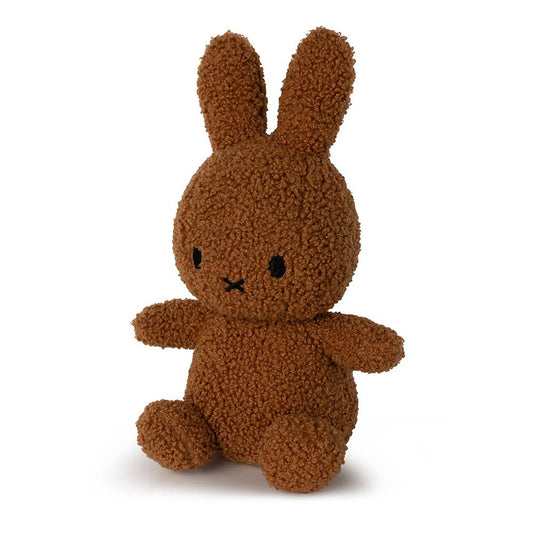 A Miffy Tiny teddy recycled soft toy in the colour cinnamon which is dark brown. This Miffy has black eyes and mouth. Miffy is 23 cm in height. The background is white. 