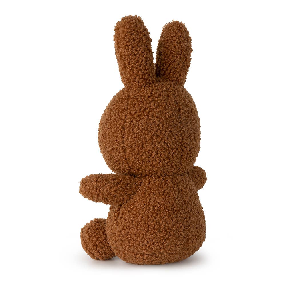 A Miffy Tiny teddy recycled soft toy in the colour cinnamon which is dark brown. This Miffy has black eyes and mouth. Miffy is 23 cm in height. The background is white. This is the back side of Miffy 