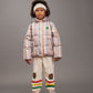 Child wearing a colorful winter outfit with a striped puffer jacket and patterned pants on a gray background