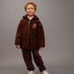 Child wearing a brown outfit with a hood on a gray background